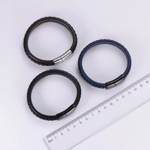 Detail of multi-layer woven leather bracelets in black, brown and blue with magnetic clasp