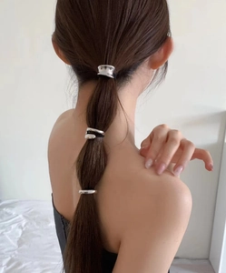 Close-up of three polished silver alloy hair rings on a low ponytail ponytail holder