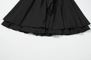 Détail de l'ourlet à volants superposés et des coutures ondulées d'une robe noire