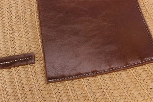 Close-up of woven straw bag texture with stitched brown faux leather patch detail