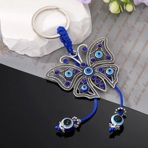 Vintage silver butterfly evil eye keychain with blue beads and braided rope on rock