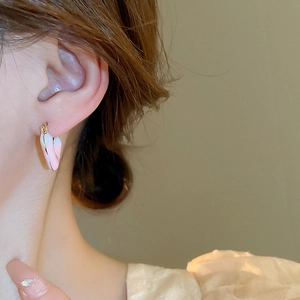 Pink gradient heart hoop earrings with gold metal finish worn by a model