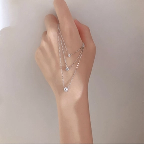 Close-up of three sizes of round zircon pendants on silver chains held in hand