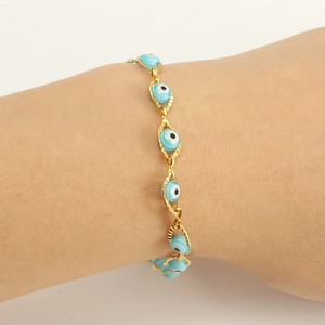 Close-up of a gold stainless steel bracelet featuring light blue Evil Eye beads on a wrist