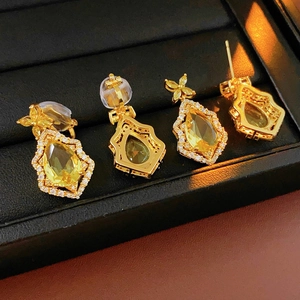 Close-up of golden teardrop earrings with yellow stones on black velvet display