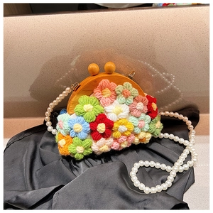 Detail of handmade crochet shell bag with multi-color floral patterns and pearl handle