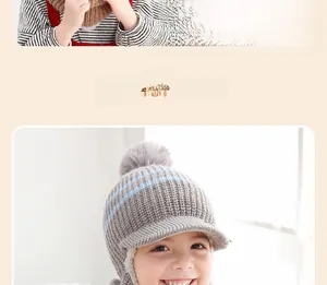 Detail der grauen Kinder-Strickmütze mit blauen Streifen und großem Kunstfell-Bommel