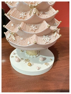 Detailed close-up of pink layered Christmas tree music box with gold bows and white snowflakes