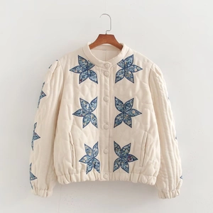 Close-up of quilted cream jacket featuring floral star applique and button-down front detail