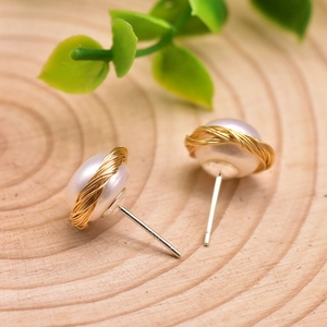 Artistic S925 silver pearl stud earrings with woven gold wire on a wooden background