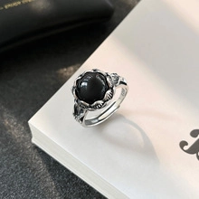 Dettaglio ravvicinato di un anello d'argento vintage con gemma nera su un libro bianco