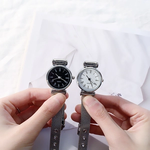 Close-up of black and white dial quartz watches with silver mesh straps held by hand