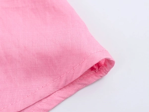 Dettaglio dell'abito rosa che mostra cuciture di qualità e tessuto traspirante in cotone lino
