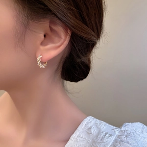 Macro detail of elegant gold hoop earrings featuring delicate inlaid white faux pearls