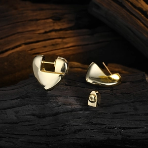 Elegant gold heart stud earrings set against a textured black background, minimalist style