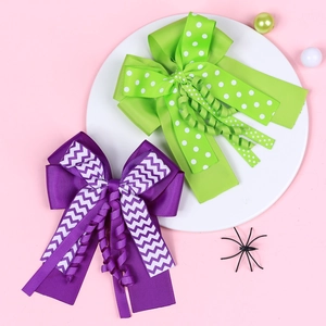 Detail of green polka dot and purple wavy bow hair clips on a pink background