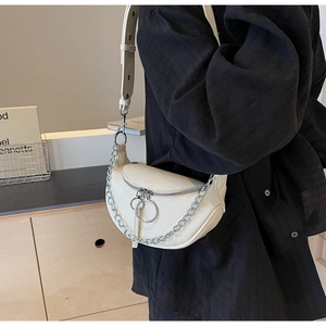 Detail view of cream half-moon bag featuring vintage texture and silver ring zippers