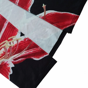 Close-up of vibrant red and white floral prints on smooth black dress fabric with stitching