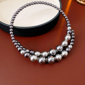 Détail du collier de perles grises à double couche avec un éclat chaleureux poli