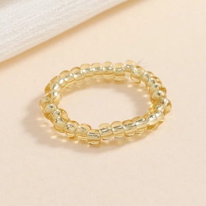 Dettaglio di un anello elastico con perline gialle trasparenti in vetro lucido fine