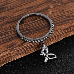 Detail of black metal ring featuring a sparkling zircon butterfly pendant and paved stones
