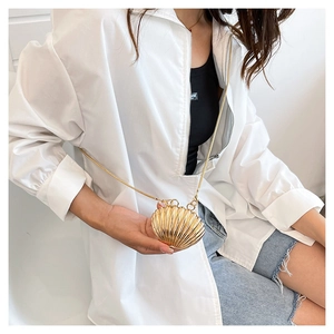 Detailed macro view of a golden shell-shaped mini crossbody bag with a sleek metal chain