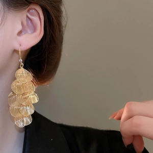 Detail view of layered gold leaf tassel earrings on a model with metallic texture
