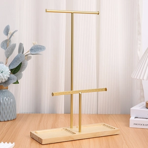 Two-tier gold metal jewelry stand with wooden base and multiple holes for earrings