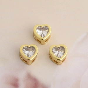 Detailed view of three golden heart charms with clear cubic zirconia for DIY jewelry