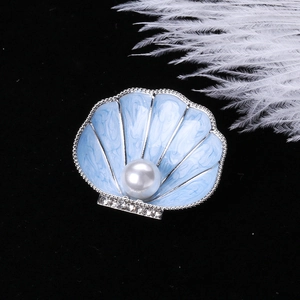 Detail of enamel shell brooch with a white pearl on a black velvet background