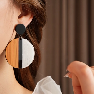 Gros plan de boucles d'oreilles rondes géométriques avec texture bois sur un mannequin