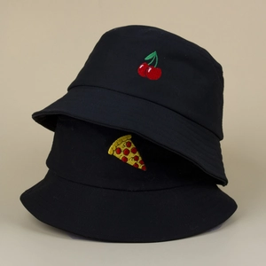 Deux bobs noirs en coton avec broderies cerise et pizza sur un fond beige minimaliste
