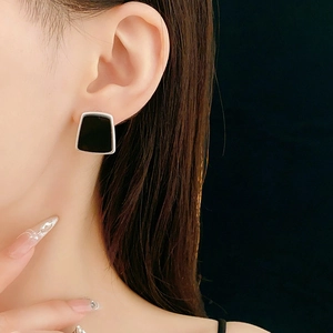 Gros plan d'une boucle d'oreille géométrique trapèze en résine portée par un modèle