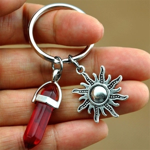 Detail view of red hexagonal crystal and silver sun charm on a stainless steel keychain