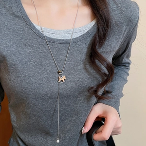 Detail of wooden rocking horse pendant and pearl drop on silver chain necklace