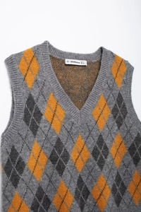 Close-up of the V-neck ribbing and argyle pattern on a grey and mustard knit sweater vest