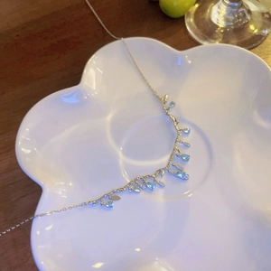 Collana a ramo in argento con pietre azzurre a goccia su piatto floreale