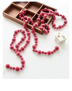 Close-up of frosted red Christmas berry garland with textured beads on wooden background