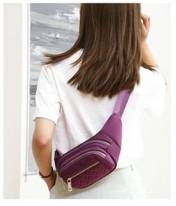 Detail of purple quilted nylon waist bag with three zipper pockets on a female model