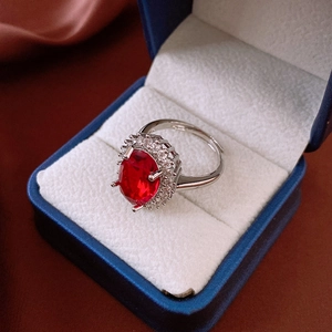 Macro shot of a red oval gemstone ring with zircon accents in a blue velvet box