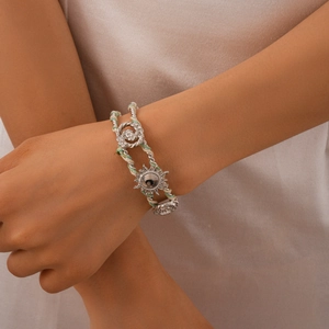 Detail of woven rope bracelet with sunflower silver metal charms worn on the wrist