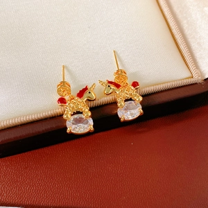 Detailed close-up of 18k gold plated unicorn stud earrings with red enamel and zircon