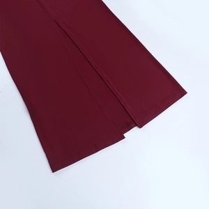 Dettaglio dell'orlo del vestito rosso scuro con cuciture pregiate e spacco laterale