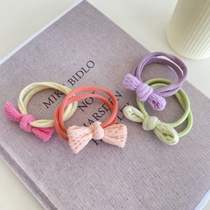 Five pastel colored bow hair ties on book cover, elastic fabric ribbons for women