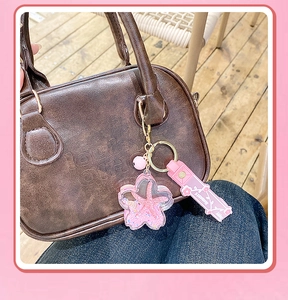 Pink starfish liquid glitter keychain with bell and strap on a brown tote bag