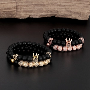 Détail de bracelets en onyx noir mat avec breloques couronne en or et or rose