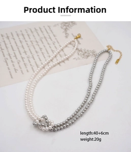 Close-up of pearl necklace featuring two interlocking gold rings and white gray beads