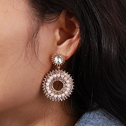 Close-up of gold double round earrings with white pearls and sparkling rhinestones