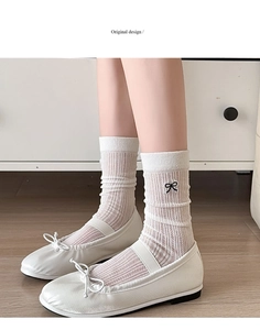 Close-up of white ribbed socks featuring black bow embroidery paired with Mary Jane shoes