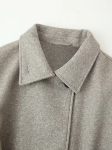Detail of the elegant lapel and wool texture on a light grey women's tailored coat